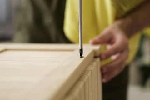 Closeup man hand using manual screwdriver and screwing screw in board Foto stock