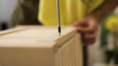 Closeup man hand using manual screwdriver and screwing screw in board Foto stock
