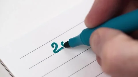Closeup man hand writes numbers 2024 with blue felt-tip pen in notebook in ruler Video stock 254751540