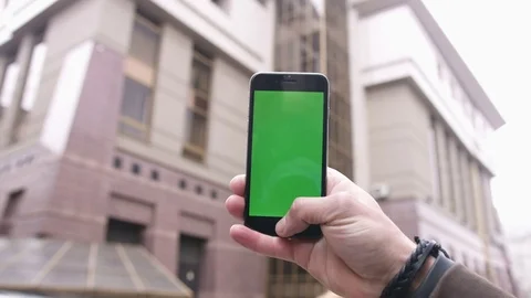 Closeup man hands holding phone with vertical green screen in the background big Stock Footage 78582514