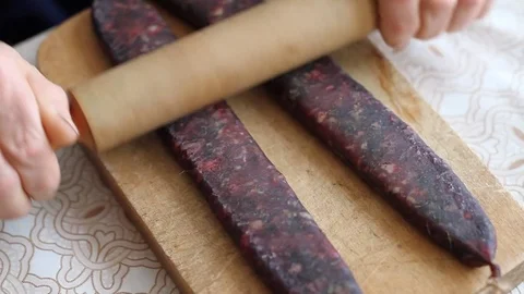 Closeup of man hands rolling over homemade sausages to make them flat for drying Stock Footage 83482522