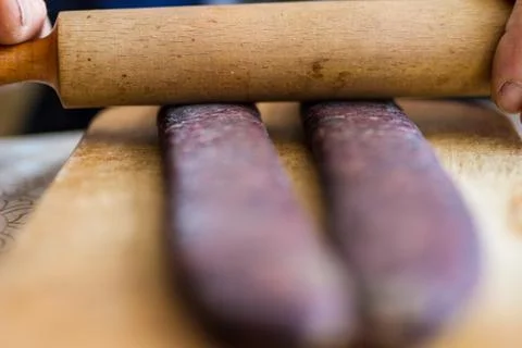 Closeup of man hands rolling over homemade sausages to make them flat for dry Stock Photos
