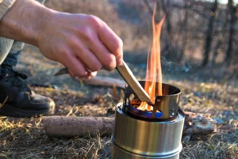 Closeup man hands sets fire with straws a in a portable wood burner in mountains Stock Photos