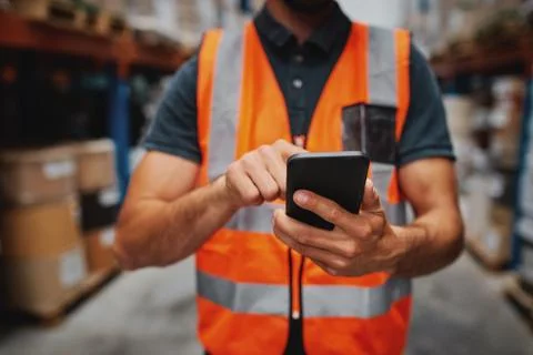 Closeup of man hands using mobile phone while in warehouse in uniform Stock Photos