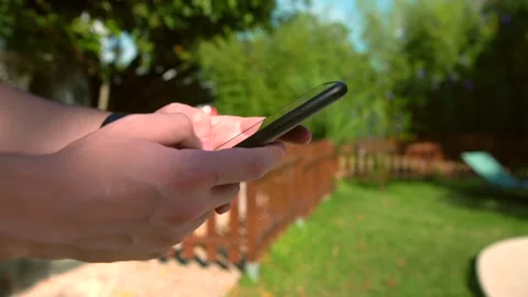 Closeup of man hands using a smartphone outdoors in a sunny garden. Stock Footage 307571039