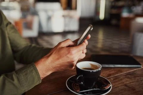 Closeup of man hands using smartphone while sitting in cafe drinking coffee Stock Photos