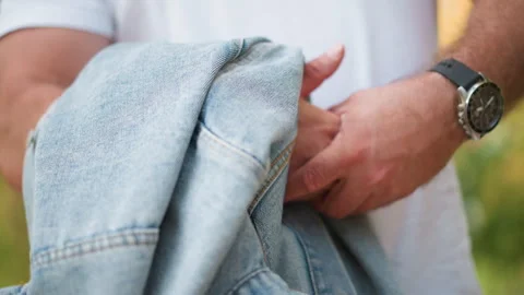 Closeup of man holding and adjusting light blue denim material with stitching Stock Footage 346723600