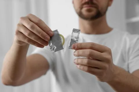 Closeup of man holding open pack with condom on blurred background 写真素材
