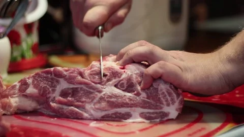 Closeup of a man in the kitchen cut the pork on a cutting Board Stock Footage 71114232
