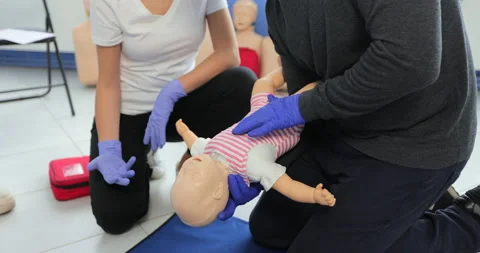 Closeup man learning how to make chest compressions on a baby dummy during the Stock Footage 163977436