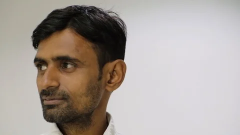 Closeup of man looking at camera then looks sideways then back at the camera  Stock Footage 100050597