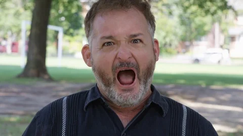 Closeup - A man looks into the camera yelling angrily - shot on RED Stock Footage 124717312