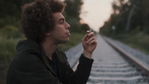 Closeup of a man Man Smoking Cigarette on the Rails Stock-Footage 258354672