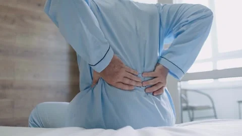 Closeup Man with pajama Feels Back Pain on the Bed at Home, Rubs Lower Back Poor Stock-Footage 336585174