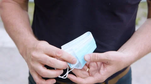 Closeup of a man picking up a facemask during the coronavirus pandemic. 스톡 동영상 131296869