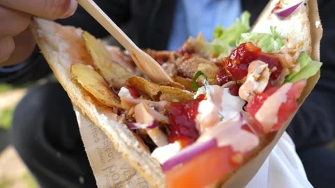 Closeup man portrait eats a kebab in a bread pita filled with chicken vegetables Video stock 304998613