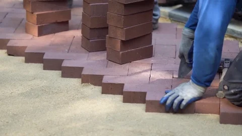 Closeup of man putting trowel between red brick pavers in a herringbone pattern Stock Footage 81993823