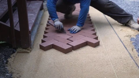 Closeup of man putting trowel between red brick pavers in a herringbone pattern Stock Footage 81996792