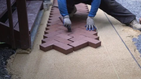 Closeup of man putting trowel between red brick pavers in a herringbone pattern Stock Footage 81996817