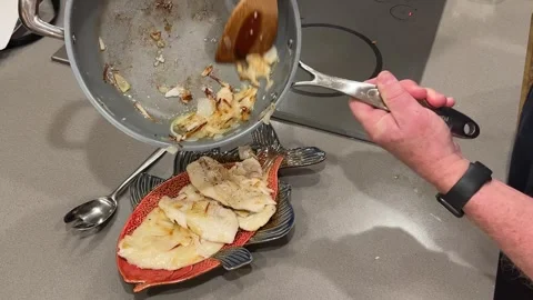 Closeup of man scraping fried onions from pan over cooked fish Stock Footage 273176553