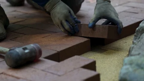 Closeup of a man setting brick pavers into place in a herringbone pattern. Stock Footage 81996760