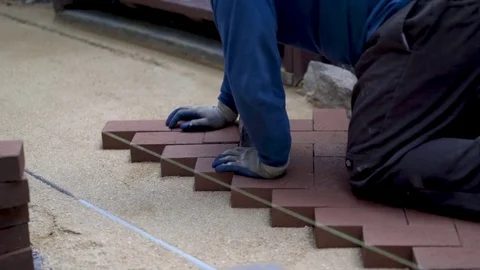 Closeup of a man setting brick pavers into place in a herringbone pattern. Stock Footage 82001840