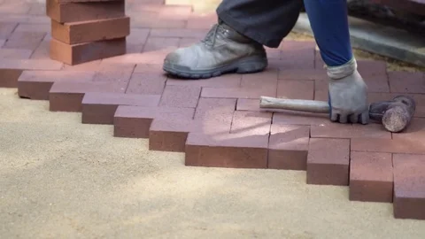 Closeup of a man setting brick pavers into place in a herringbone pattern. Stock Footage 82006344