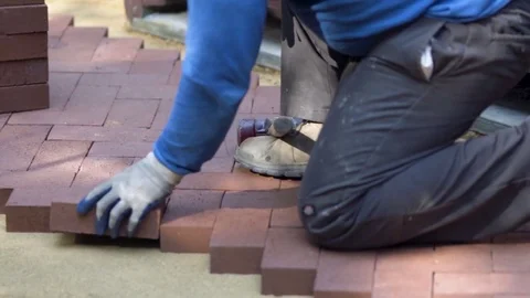 Closeup of a man setting brick pavers into place in a herringbone pattern. Stock Footage 82041580