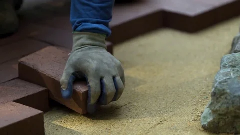 Closeup of a man setting brick pavers into place in a herringbone pattern. Stock Footage 82096237