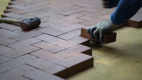 Closeup of a man setting brick pavers into place in a herringbone pattern. Stock Footage 82119819