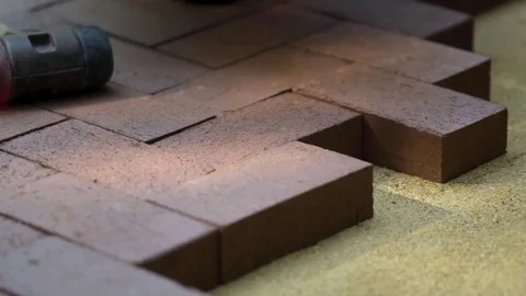 Closeup of a man setting brick pavers into place in a herringbone pattern. Stock Footage 82183539