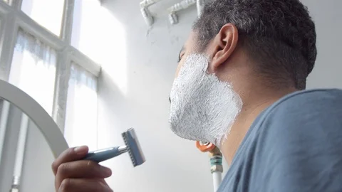Closeup of man shaving with foam Side view and then camera moves to show his Stock Footage 127040693