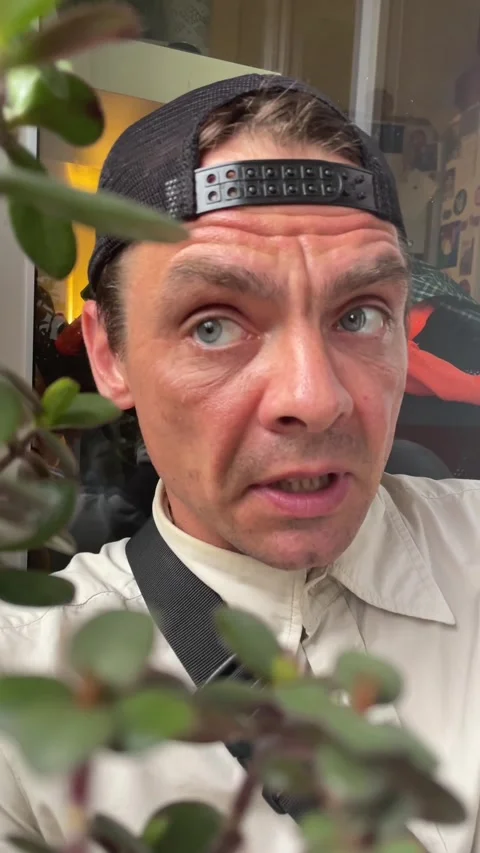 Closeup of man speaking with surprised expression near window and plant, with Видео 344586293