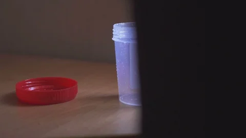 Closeup of a man standing at a table and pisses into a container for urine Video stock 90175685