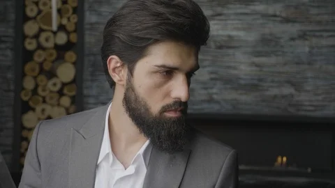 Closeup man with thick beard sits looks aside by fireplace Stock Footage 103925125