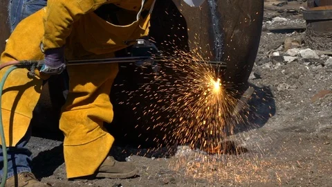Closeup of a man torch cutting large scrap metal in junkyard in slow motion Stock Footage 100838380