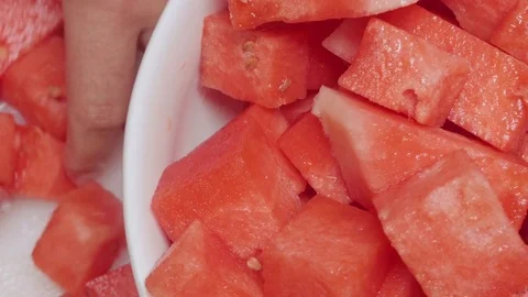 Closeup of a Man Transferring Chopped Watermelon into a White Serving Bowl Stock Footage 79045875