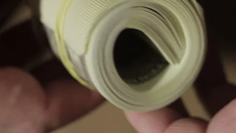 Closeup of a man twisting a roll of hundred-dollar bills in his fingers Video stock 83293329