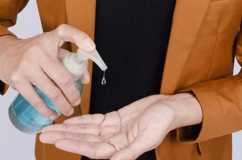 Closeup of man using wash hand sanitizer gel pump dispenser, Hygiene and Co.. Stock Photos