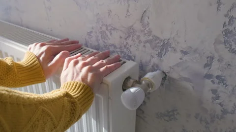 Closeup of man warming his hands in yellow sweater on the heater at home during Stock Footage 254514882