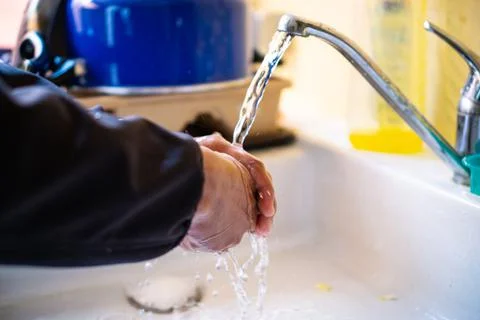 Closeup man washing hands in sink before cooking in kitchen Stock Photos
