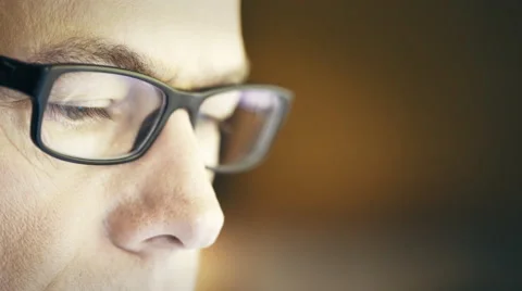 Closeup of a man wearing glasses looking at a computer screen 4k Stock Footage 64905697