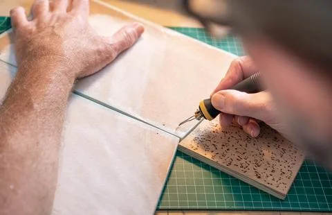Closeup of a man working with pyrographer burning wood making artwork craft at Stock Photos