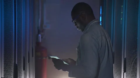 Closeup of man working with tablet and examining data server, standing in dark Stock Footage 161744766