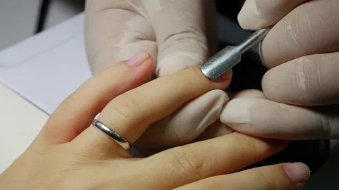 Closeup The manicurist pushes back the cuticles on the nails and prepares for Video stock 81397237