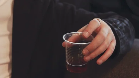 Closeup of a man's hand holding a plastic disposable glass with tea. On the Stock Footage 105639806