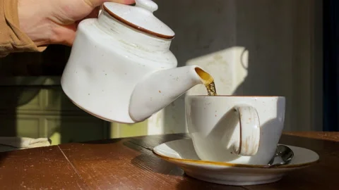 Closeup man's hand pours tea from a porcelain teapot into a white cup. Video Stock-Footage 149692687