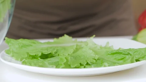 Closeup of a man's hand putting halves of cherry tomatoes on lettuce leaves in a Stock Footage 101807280