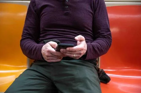 Closeup of man's hands checking cellphone on subway Stock Photos
