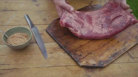 Closeup of man's hands elegantly putting a raw beef brisket on wooden plat Vídeos de archivo 136516686